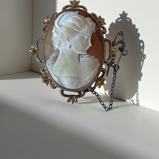 A vintage shell cameo brooch with a woman's profile, set in ornate gold framing and delicate details.