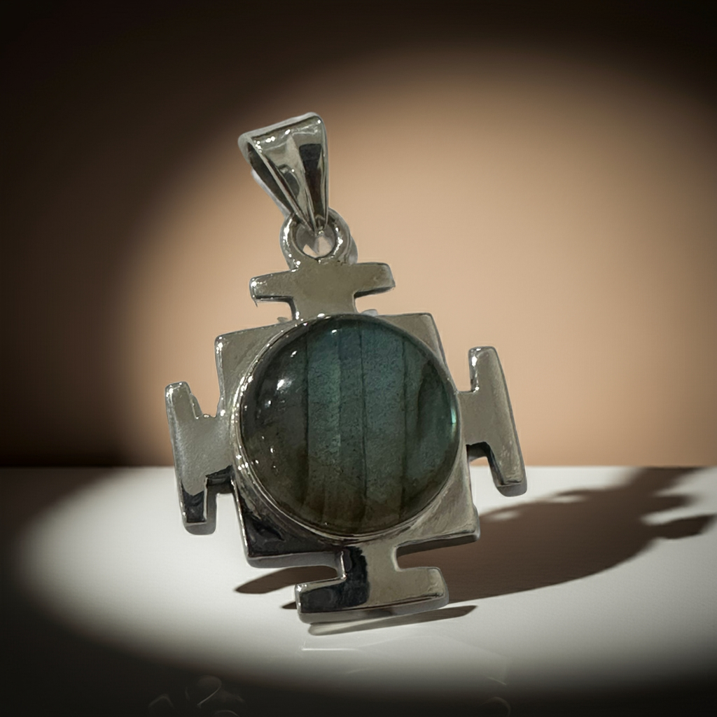 Polished silver cross pendant featuring labradorite cabochon with deep blue and green hues, modern design.