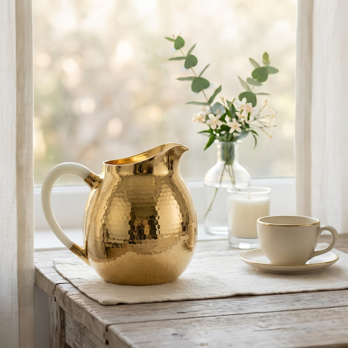 Close-up of the cream handle and pour spout on the hammered silver-tone pitcher